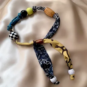 Collana a foulard con stampa leopardata e perle colorate su sfondo di seta champagne