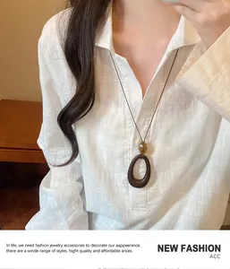 Retro style long pendant necklace with brown oval wood and yellow bead on linen shirt