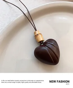 Macro detail of a dark brown heart pendant with bamboo joint decor and a fine rope chain