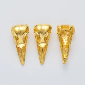 Macro detail of three golden bird skull metal pendants with realistic bone textures