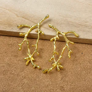 Detailed close-up of two golden branch-shaped pendants showing natural bark textures on wood