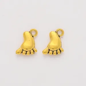 Detailed view of vintage gold baby feet pendants with antique texture for DIY jewelry