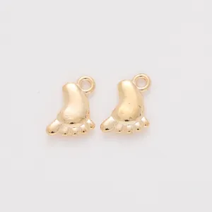 Macro shot of two polished gold baby foot charms for DIY jewelry making accessories