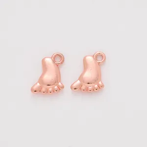 Close-up of rose gold baby feet charms for DIY jewelry making with smooth metal finish