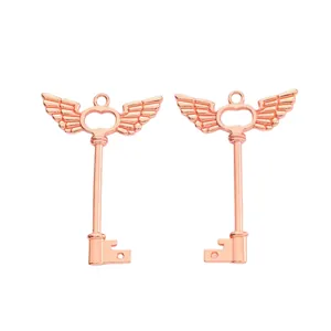 Detalle macro de colgantes de llave con alas en oro rosa de aleación pulida para joyería DIY