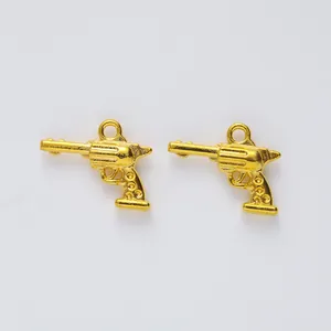 Detalle de dos colgantes de revólver dorados en aleación de zinc para joyería artesanal