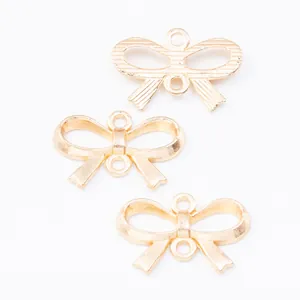Close-up of three gold bow-shaped alloy connectors for DIY jewelry making with dual loops