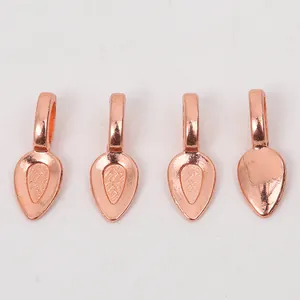 Detailed view of four teardrop-shaped rose gold metal pendant trays for DIY jewelry making