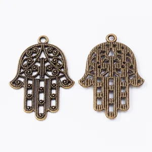 Macro shot of two vintage bronze alloy Hamsa hand charms with hollow carvings for DIY jewelry