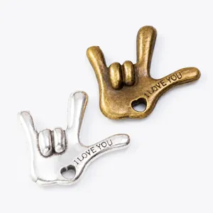 Detail of I Love You hand gesture charms with heart cutout in bronze and silver finish