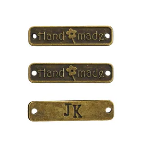 Drei rechteckige Vintage-Metallanhänger in Bronze mit Handmade-Schriftzug und Blumenmuster