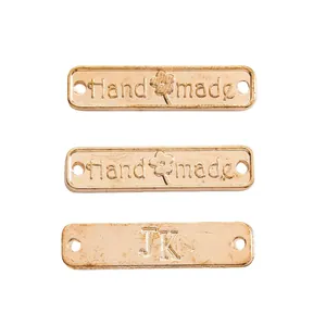 Makro-Detail von roségoldenen Metall-Etiketten mit Handmade- und JK-Gravur für DIY