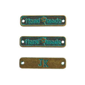 Makro-Detail von Vintage Bronze 'Hand made' und 'JK' Metalletiketten für DIY-Bastelarbeiten