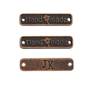 Makroaufnahme von drei bronzefarbenen DIY-Anhängern mit graviertem Handmade-Schriftzug