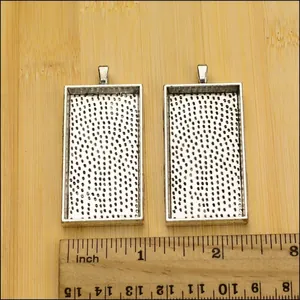 Detail of two silver rectangle alloy pendant trays with textured base and top loop