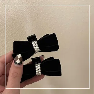 Vue détaillée de deux mini barrettes à nœuds en velours noir avec perles élégantes