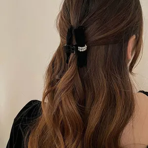 Détail d'une pince à cheveux en velours noir ornée de perles montrée sur un mannequin