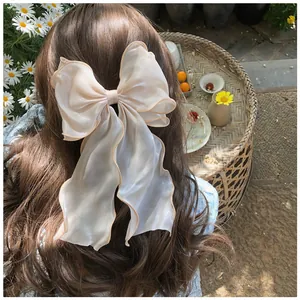 Barrette nœud élégante en organza blanc sur de longs cheveux châtains ondulés