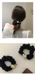 Detail of black elastic hair scrunchies with heart pearl charms and handmade metal tag