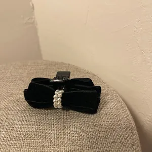 Gros plan sur pince à cheveux nœud en velours noir avec perles blanches et tissu texturé