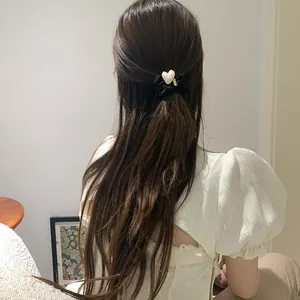 Elegant heart-shaped pearl hair tie worn on a ponytail for a minimalist chic style