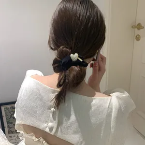 Detail of elegant black velvet hair scrunchie with a gold-rimmed heart pearl accessory
