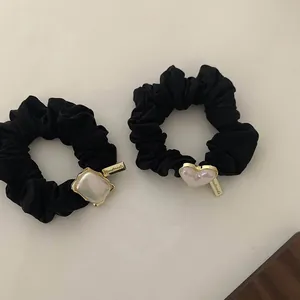 Detailed macro view of handmade black elastic hair scrunchies with heart pearl charms