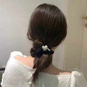 Elegant black scrunchie with heart pearl charm on hair in a semi-updo ponytail
