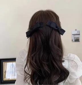 Elegant pair of black ribbon bow hair clips on brunette hair, soft fabric hair accessories