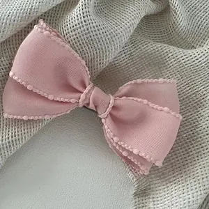 Detailed macro view of pink double-layered ribbon hair clip with delicate lace edge