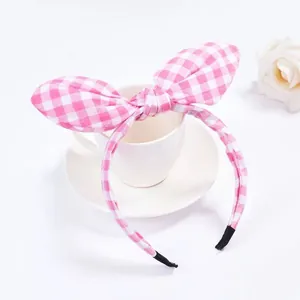 Cerchietto a quadretti rosa e bianchi con grande fiocco su una tazza di ceramica bianca