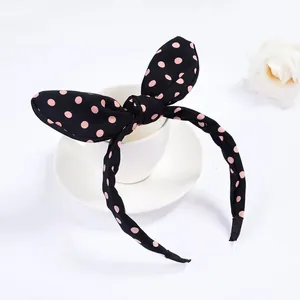 Dettaglio del cerchietto con orecchie di coniglio nero a pois rosa su sfondo bianco