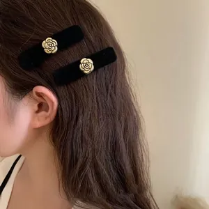 Vintage black flocked hair clips with gold camellia flower relief on brown wavy hair