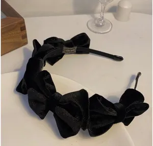 Elegant black velvet headband with five bows on a white plate, stylish hair accessory