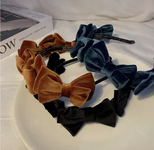 Three velvet bow headbands in caramel, blue and black displayed on a white plate