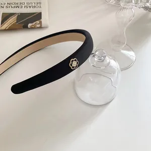 Détail du serre-tête noir en tissu orné d'une fleur de camélia avec revêtement antidérapant