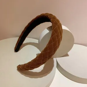Nahaufnahme von dunkelbraunem Samt-Stirnband mit Rautensteppmuster auf weißem Display