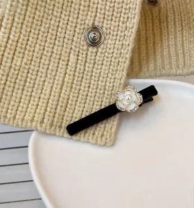 Detail der Samt-Kamelie-Haarspange mit Perle, Kristallen und LOVE DAYS Anhänger