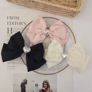 Detail of pink, black, and cream bow hair clips with silver heart-shaped metal accents