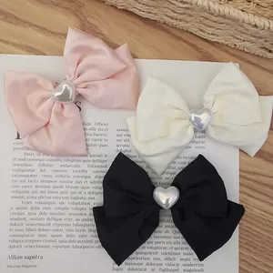 Detail view of pink, white, and black satin bow hair clips with silver heart centers