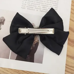 Detail view of large black satin bow hair clip featuring a durable metal alligator grip