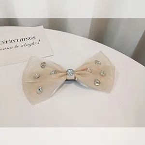Elegant champagne organza bow hair clip featuring sparkling zircon stones and a center crystal
