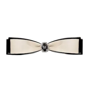 Detail of a layered black and white satin bow clip with a vintage black gemstone and crystals