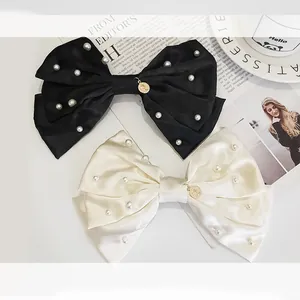 Detail of satin bow hair clips with white pearls and gold coin charms in elegant setting