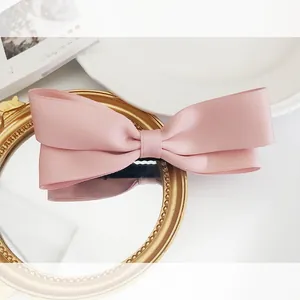 Close-up of a pink satin bow hair clip with elegant layered fabric and spring fastener