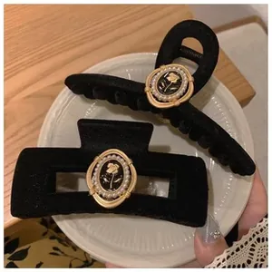Detail van fluwelen haarklemmen met gouden roosgesp en parels op keramische plaat