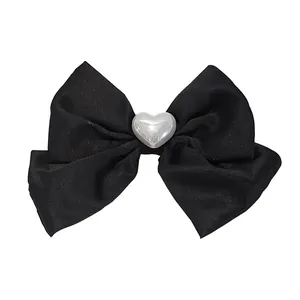 Elegant black fabric bow hair clip featuring a pearlescent white heart center accessory