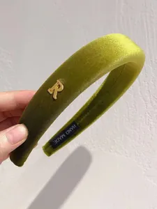 Detail view of avocado green velvet headband with gold letter R and handmade label