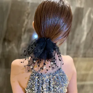 Elegante elastico per capelli in pizzo nero con perline bianche su una modella
