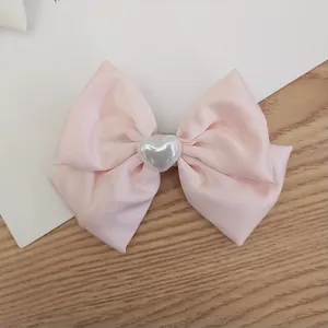 Pink satin bow hair clip with silver heart center decoration for elegant styling